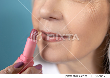Beautiful aging woman with lipstick doing makeup 102828472