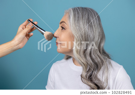 Beautiful smiling senior woman doing makeup Beautiful smiling senior woman doing makeup 102828491