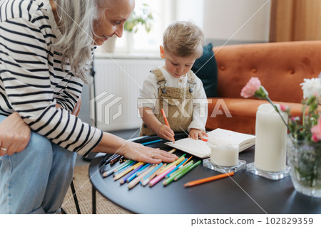 Grandson drawing in a notepad with his grandmother. Grandson drawing in a notepad with his grandmother. 102829359