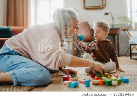 Grandmother playing with her little grandson,building a block set. Grandmother playing with her little grandson,building a block set. 102829490