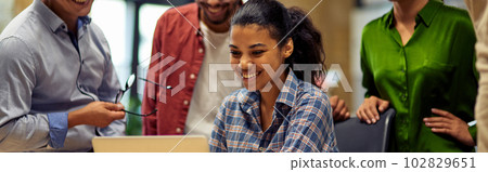 Group of happy multiracial business people looking at laptop screen, discussing project results and smiling while working together in the modern office or coworking space 102829651