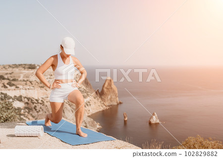 Fitness woman sea. Outdoor workout on yoga mat roller in park near to ocean beach. Female fitness pilates yoga routine concept. Healthy lifestyle. Happy fit woman exercising with rubber band in park. 102829882