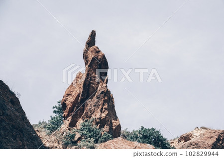 A close up of rocks that look like the beak of a bird or a sharp nose The picturesque volcanic coast of the island on the ocean waters - sharp rocks, dark stones 102829944
