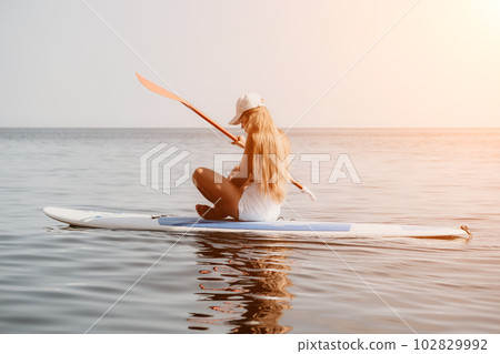 Woman sea sup. Close up portrait of happy young caucasian woman with long hair looking at camera and smiling. Cute woman portrait in bikini posing on sup board in the sea Woman sea sup. Close up portrait of happy young caucasian woman with long hair looking at camera and smiling. Cute woman portrait in bikini posing on sup board in the sea 102829992
