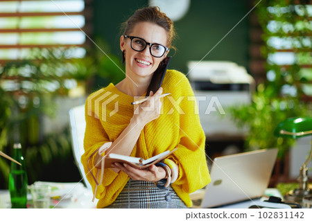happy business owner woman in green office talking on phone 102831142