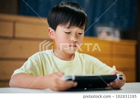 Elementary school boy playing a game on a home video game console Elementary school boy playing a game on a home video game console 102831195