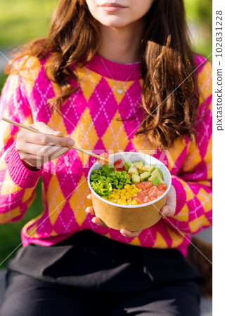 A woman eating a poke 102831228