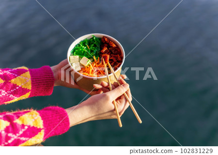 A woman eating a poke 102831229
