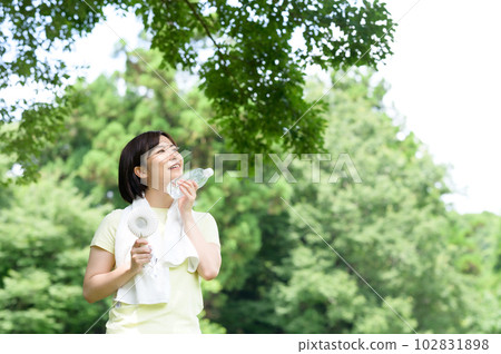 Woman with electric fan and water in the shade 102831898