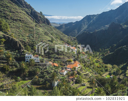 View over small village La Laja, red and white rural houses in lush green valley with palm trees. Landscape near national park Garajonay on La Gomera, Canary Islands, Spain. 102831921