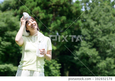 Woman with towel and water in the park 102832178