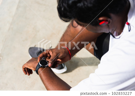 Close up Asian young athlete sport runner black man wear modern time smart watch he sitting resting before training running at the outdoor street health park, healthy exercise before workout concept Close up Asian young athlete sport runner black man wear modern time smart watch he sitting resting before training running at the outdoor street health park, healthy exercise before workout concept 102833227