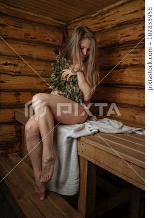 Young woman relaxing in a sauna dressed in a towel and birch broom Young woman relaxing in a sauna dressed in a towel and birch broom 102833958
