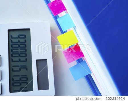 A blue file and a calculator on the table A blue file and a calculator on the table 102834614