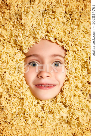 Funny image with cute face of beautiful little girl, child peeking out noodles background. Fun, food, nutrition, fantasy Funny image with cute face of beautiful little girl, child peeking out noodles background. Fun, food, nutrition, fantasy 102834762