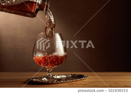 Brandy is poured into a snifter glass. 102836553