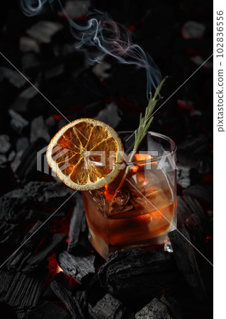 Old-fashioned cocktail with ice, dried orange slice, and rosemary. 102836556
