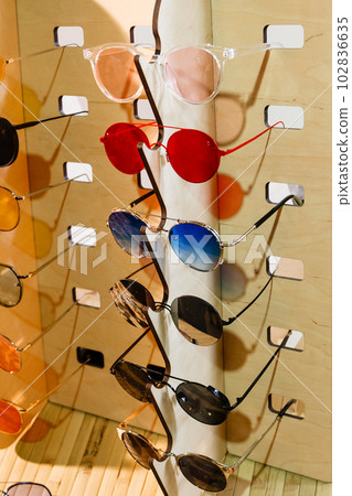 large selection of sunglasses and glasses on a stand 102836635