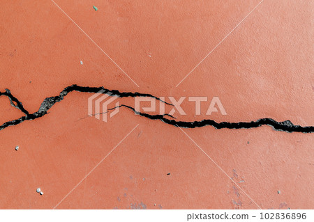 Crack in red-painted asphalt on a sports field 102836896