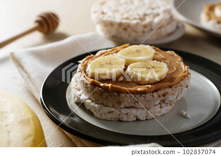 Rice cake with banana and peanut butter, healthy protein snack Rice cake with banana and peanut butter, healthy protein snack 102837074