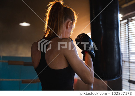 Women self defense girl power. Strong woman fighter training punches on boxing ring. Healthy strong girl punching boxing bag. Training day in boxing gym. Strength fit body workout training Women self defense girl power. Strong woman fighter training punches on boxing ring. Healthy strong girl punching boxing bag. Training day in boxing gym. Strength fit body workout training 102837178