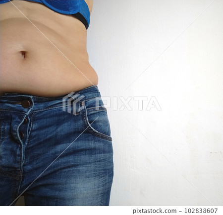 Saggy belly. Folds of leather and fat on the sides hanging over the waist of the jeans. A figure spoiled by overeating or pregnancy. Obesity and Diabetes. Unhealthy Lifestyle. Cellulite flabby muscles 102838607