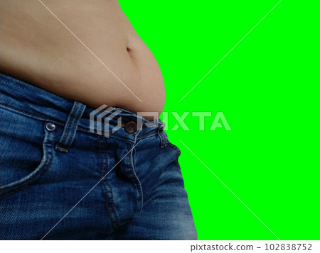 Saggy belly. Folds of leather and fat on the sides hanging over the waist of the jeans. Overeating or pregnancy. Obesity and Diabetes. Green chroma key background. Cellulite flabby muscles Saggy belly. Folds of leather and fat on the sides hanging over the waist of the jeans. Overeating or pregnancy. Obesity and Diabetes. Green chroma key background. Cellulite flabby muscles 102838752