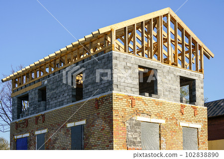 Unfinished residential house with brick and block walls and a wooden beam roof structure Unfinished residential house with brick and block walls and a wooden beam roof structure 102838890