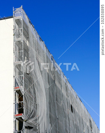 Multistorey apartment building facade renovation and thermal insulation, scaffolding with safety net 102838895