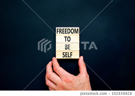 Freedom to be self symbol. Concept words Freedom to be self on wooden blocks on a beautiful black table black background. Businessman hand. Business, psychological freedom to be self concept. 102838928
