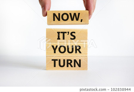 Now it is your turn symbol. Concept words Now it is your turn on wooden blocks. Businessman hand. Beautiful white table, white background, copy space. Business and now it is your turn concept. 102838944