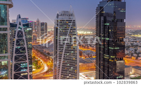 Tall residential buildings at JLT aerial day to night timelapse, part of the Dubai multi commodities centre mixed-use district. 102839863