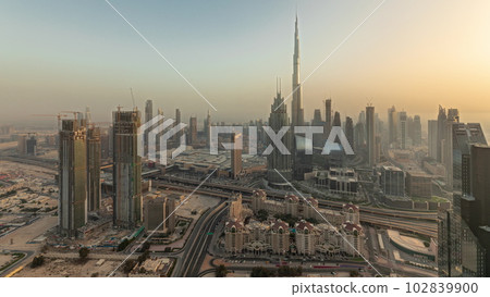 Panorama showing aerial view of tallest towers in Dubai Downtown skyline and highway timelapse. 102839900