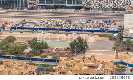 Aerial view of a parking lot with many cars behind a blue fence timelapse Aerial view of a parking lot with many cars behind a blue fence timelapse 102839978