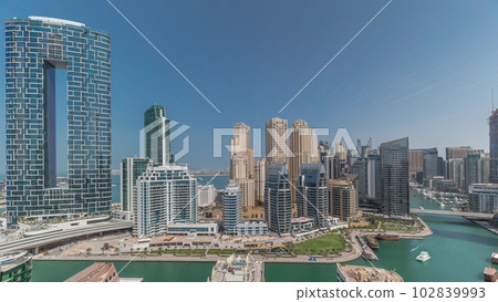 Dubai Marina with several boat and yachts parked in harbor and skyscrapers around canal aerial timelapse. Dubai Marina with several boat and yachts parked in harbor and skyscrapers around canal aerial timelapse. 102839993
