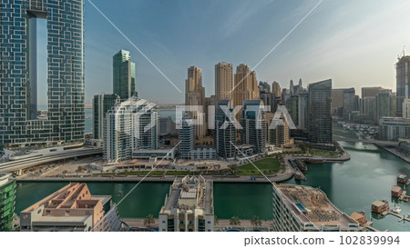 Panorama showing Dubai Marina with several boats and yachts parked in harbor and skyscrapers around canal aerial morning timelapse. Panorama showing Dubai Marina with several boats and yachts parked in harbor and skyscrapers around canal aerial morning timelapse. 102839994
