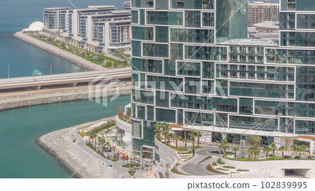 Promenade and Dubai cityscape seen from Dubai marina timelapse. Aerial view to JBR district and Bluewaters Island behind Promenade and Dubai cityscape seen from Dubai marina timelapse. Aerial view to JBR district and Bluewaters Island behind 102839995