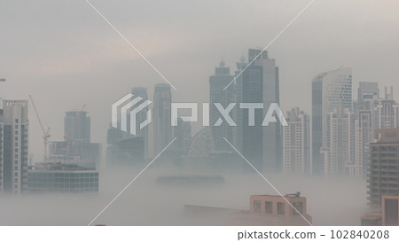 Dubai skyscrapers with morning fog in business bay district night to day timelapse. 102840208
