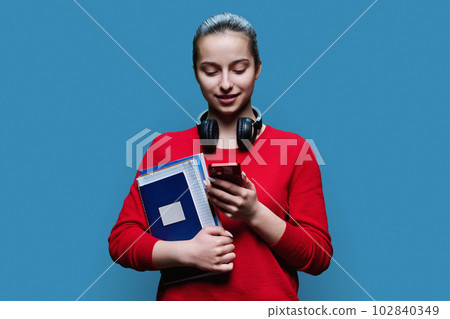 Portrait of teen girl high school student with smartphone on blue background 102840349