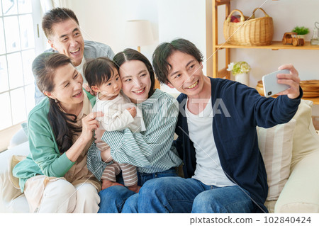 A family of three generations taking selfies with a smartphone 102840424