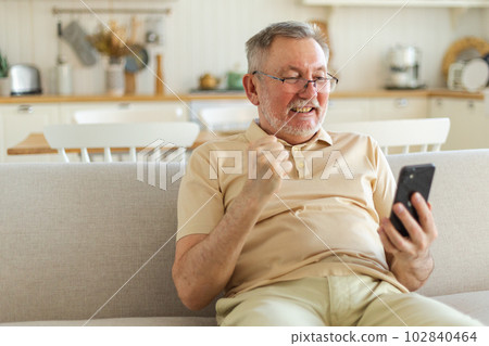Middle aged senior man euphoric winner with smartphone. Older mature grandfather looking at cell phone reading great news getting good result winning online bid feeling amazed. Winning gesture Middle aged senior man euphoric winner with smartphone. Older mature grandfather looking at cell phone reading great news getting good result winning online bid feeling amazed. Winning gesture 102840464