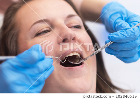 close up young woman receiving dental treatment from a qualified dentist using dental tools in a modern dental clinic. close up young woman receiving dental treatment from a qualified dentist using dental tools in a modern dental clinic. 102840519