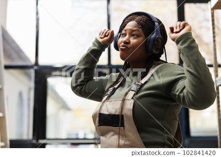 Warehouse supervisor enjoying listening music, working at clients packages before start shipping process in storehouse. Stockroom worker wearing headphones, dancing during work break 102841420