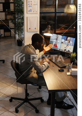 Executive manager having remote conversation with team during online videocall meeting conference, discussing marketing strategy. Diverse coworkers working late at night in startup office 102841648