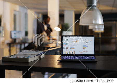 Laptop computer showing marketing statistics on screen, discussing company inves tment plan. Executive managers working overhours at financial growth report in startup office. Business concept Laptop computer showing marketing statistics on screen, discussing company inves tment plan. Executive managers working overhours at financial growth report in startup office. Business concept 102841652