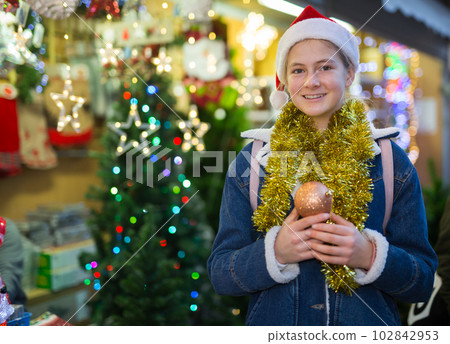 Cheerful teenage girl standing on city street fair on Christmas Eve Cheerful teenage girl standing on city street fair on Christmas Eve 102842953