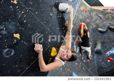 Female fitness climber training at bouldering gym. Female fitness climber training at bouldering gym. 102842963