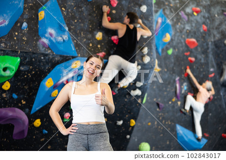 after successful workout, young female sportswoman poses near bouldering wall 102843017