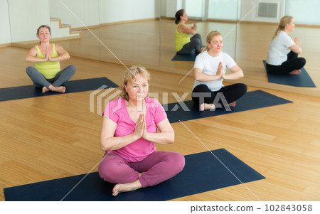 Senior women meditating together at yoga class Senior women meditating together at yoga class 102843058