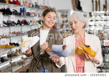 Mom with an adult daughter choose and buy fashionable high heeled shoes in a shoe store 102843081